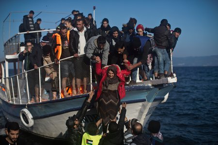 Flüchtlinge auf Lesbos / © 2015 KNA, www.kna-bild.de - Nutzungsrechte vorbehalten., Marko Drobnjakovic Flüchtlinge und Freiwillige helfen einer Frau von einem Holzboot am Strand von Lesbos am 7. November 2015.